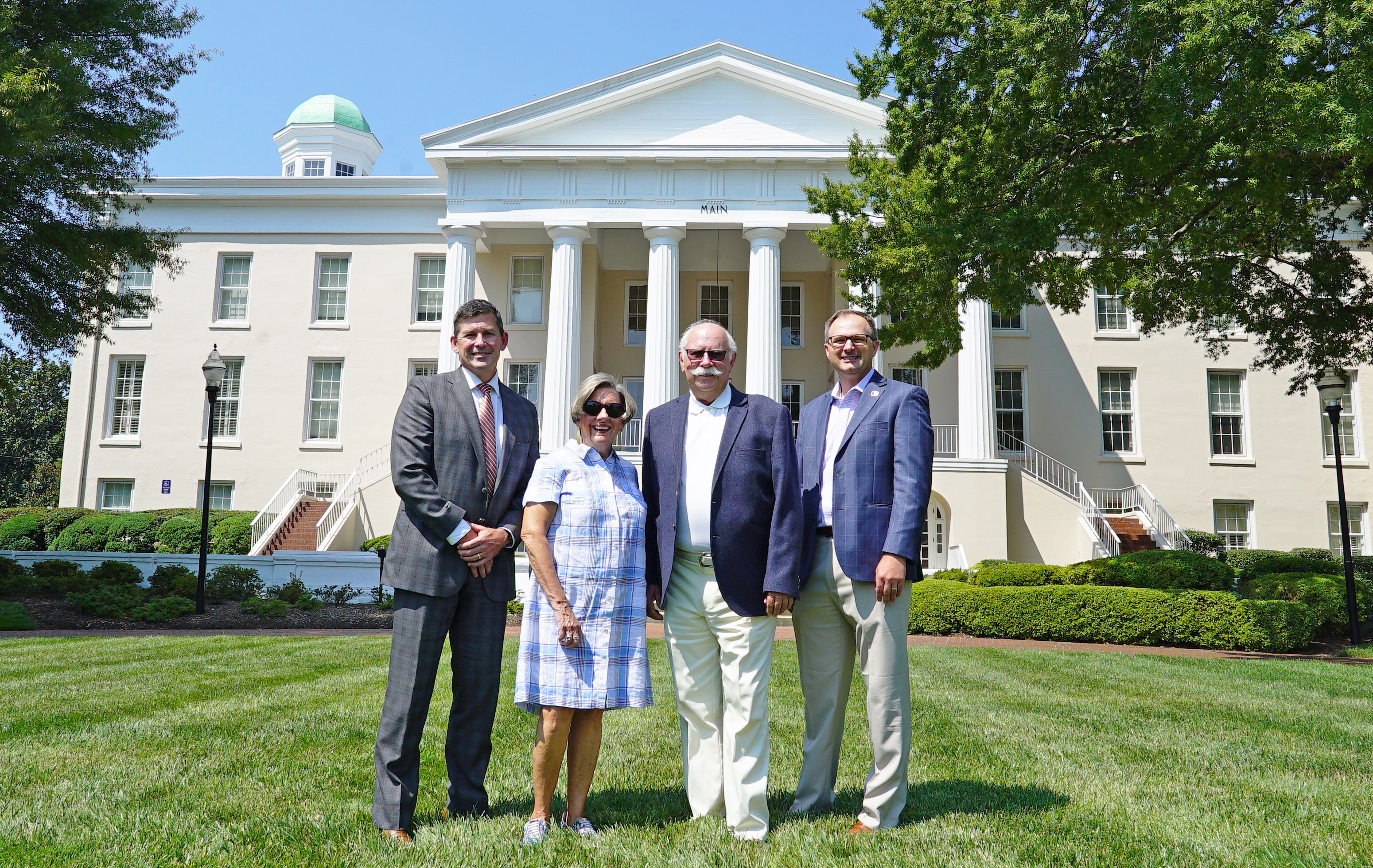 (L-R) Dr. Tim Brewer, Carol Childress, Frank Childress, and James Hogan stand in front of Mitchell's historic Main Building on the Statesville Campus.