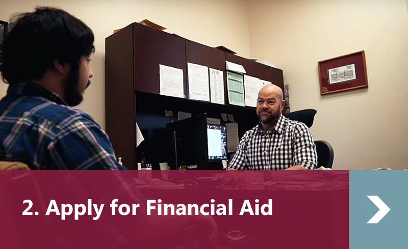2. Apply for Financial Aid - male student talking to male financial aid advisor in office.