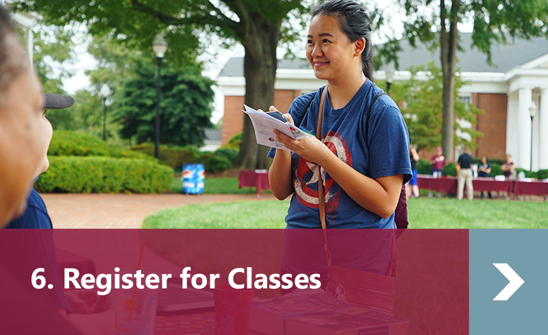 6. Register for Classes - Female student visits advising table at orientation.