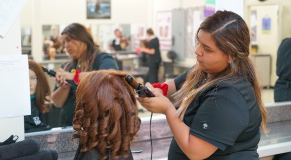 A Cosmetology student practices on a mannequin 